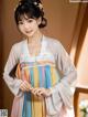 A woman wearing a colorful hanbok standing in front of a window.