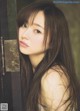 A woman with long brown hair leaning against a door.