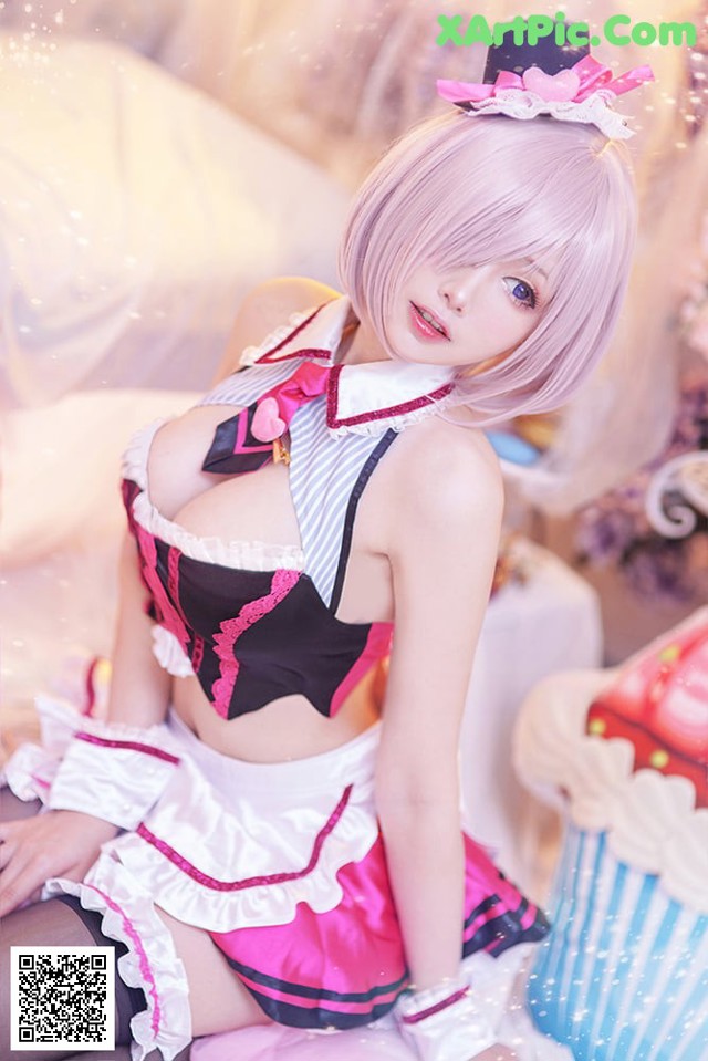 A woman in a maid outfit sitting on a bed.