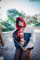 A woman in a red hooded jacket is posing for a picture.