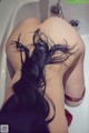 A woman with long black hair laying in a bathtub.