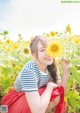 A woman sitting in a field of sunflowers holding a sunflower.