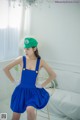 A woman in a blue dress and a green hat posing for a picture.