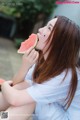 A woman is eating a slice of watermelon.