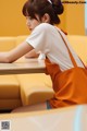 A woman sitting at a table with an orange bag.